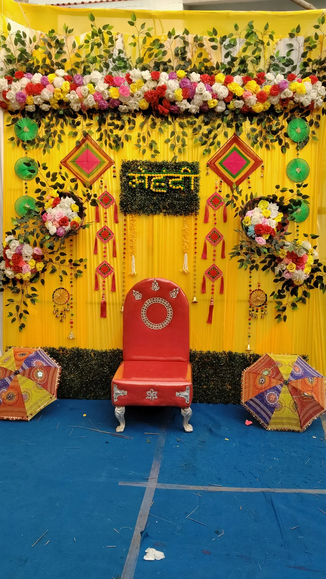 Yellow green mehendi backdrop with red chair decoration